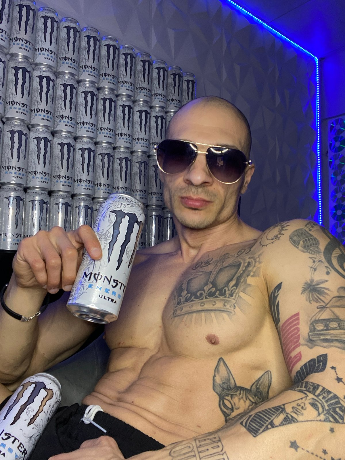 Man poses with Monster Energy cans in LED-lit room
