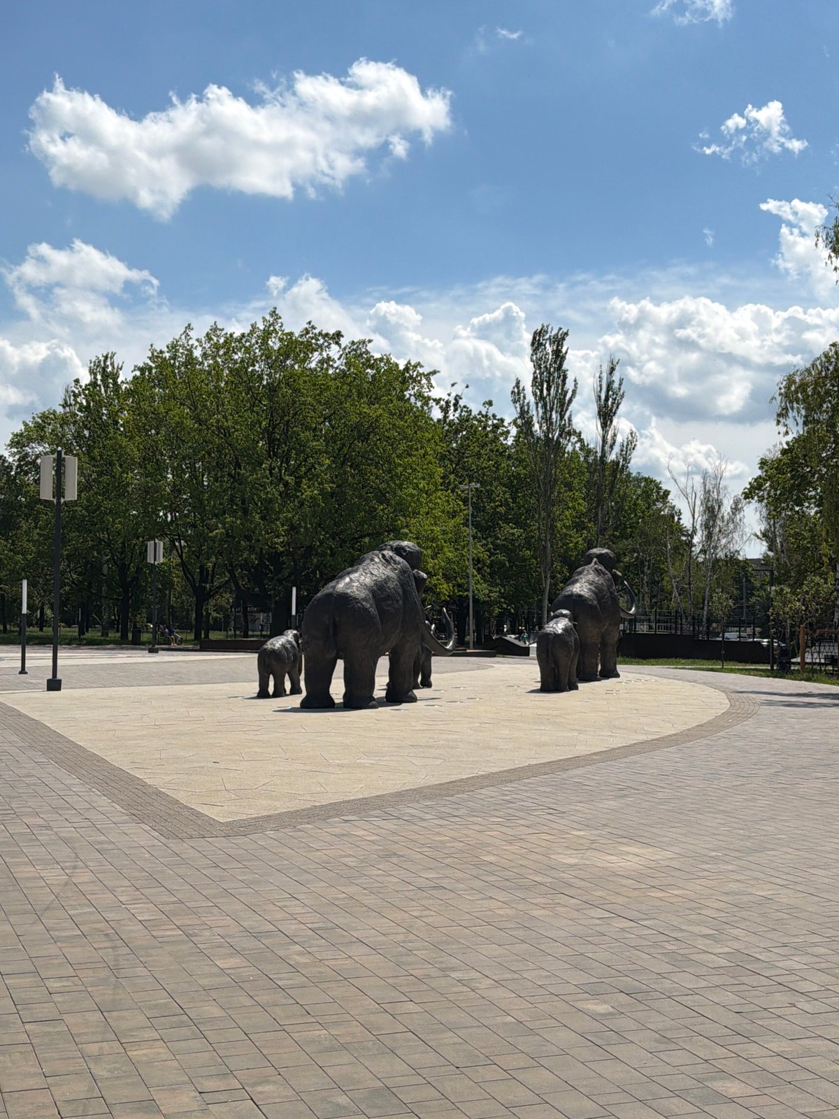 Kid explores a sunny urban park with elephant sculptures