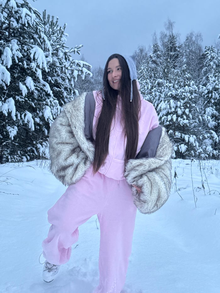Woman in pink poses in snowy Russian forest