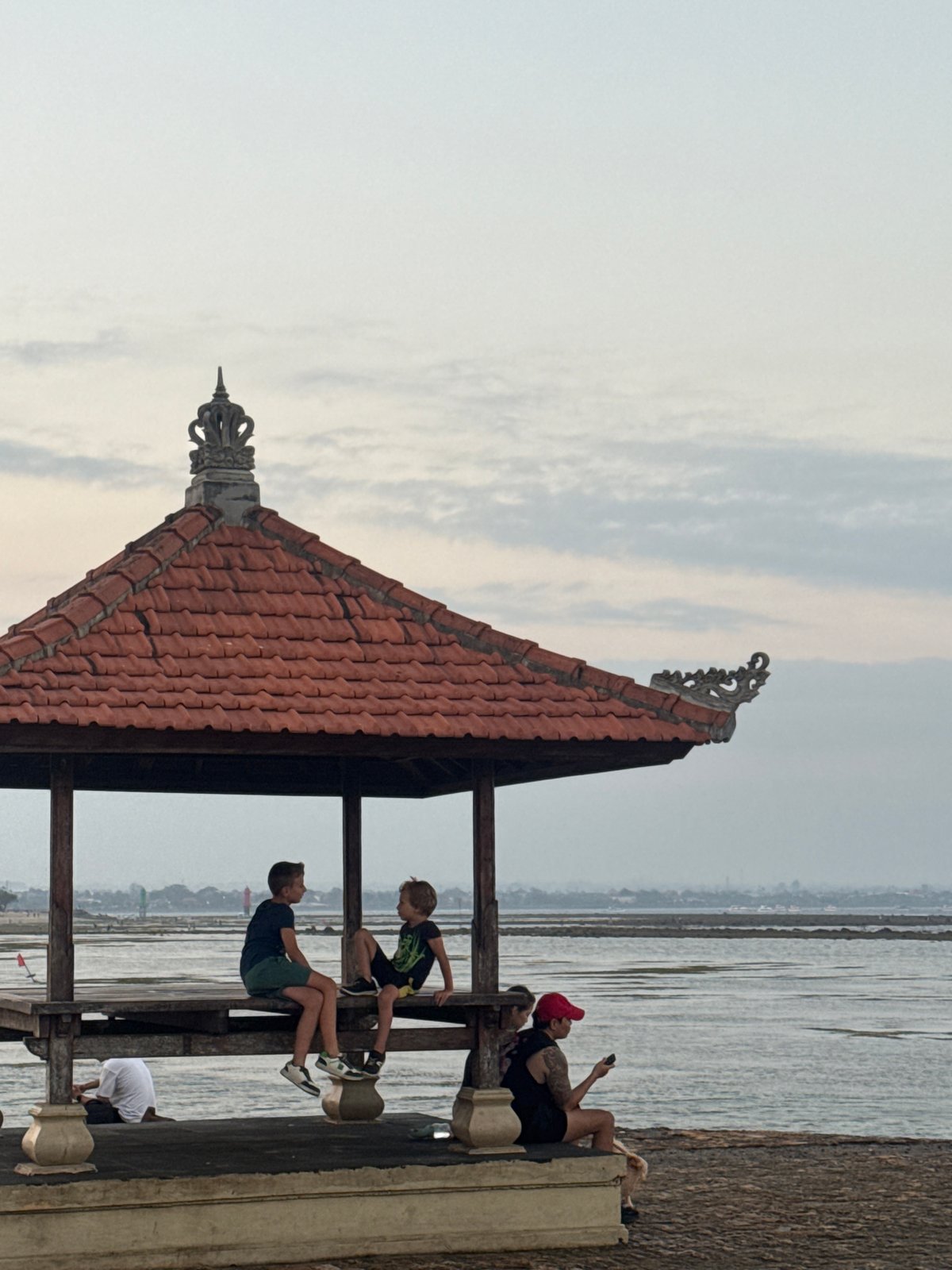 Conversation inside a carved Balinese pavilion in Denpasar