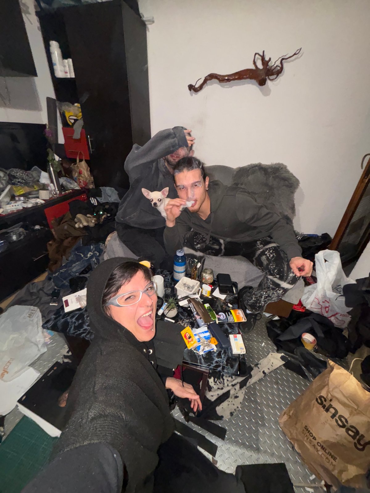 Two people rest on cluttered floor with dog in Sofia