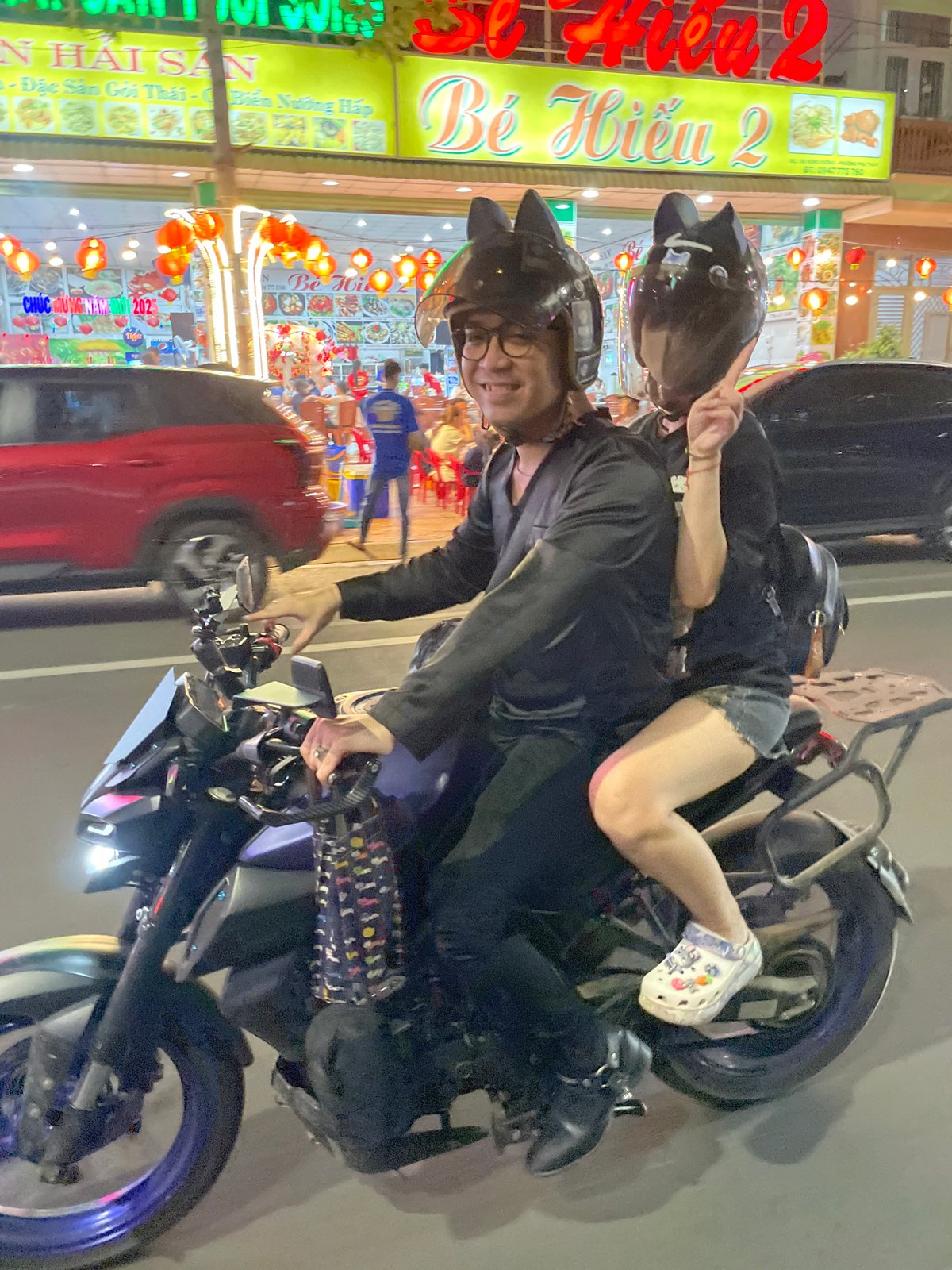 Two riders navigate rainy night streets in Vietnam