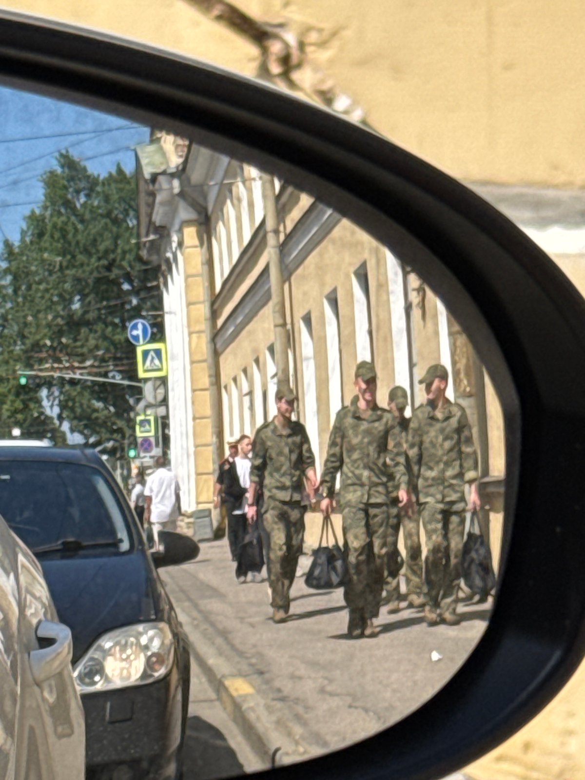 Military figures on foot near a golden-domed Saint Petersburg church