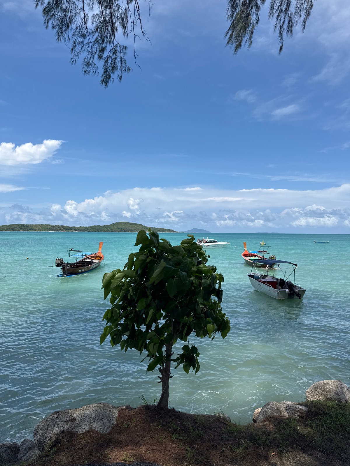 Calm morning at Rawai Bay, long-tail boats on turquoise water