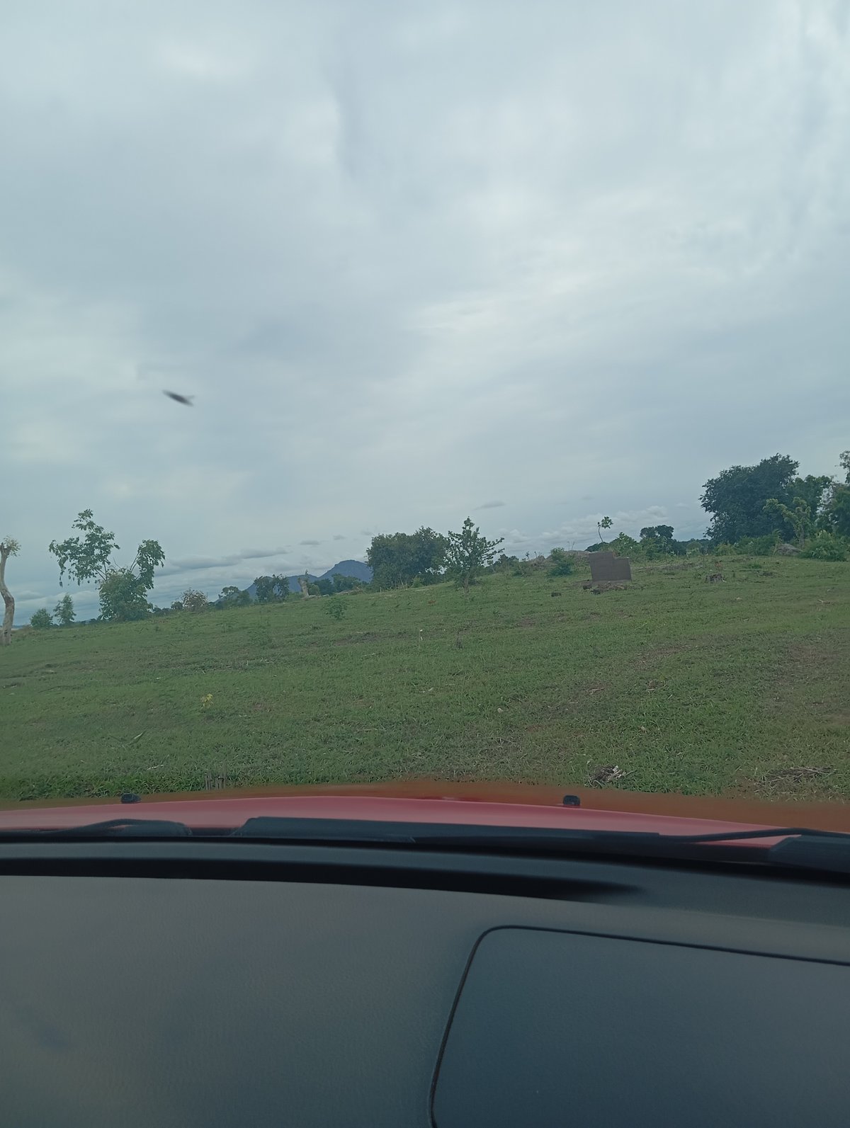 Road trip through Nigerian savanna farmland on an overcast afternoon