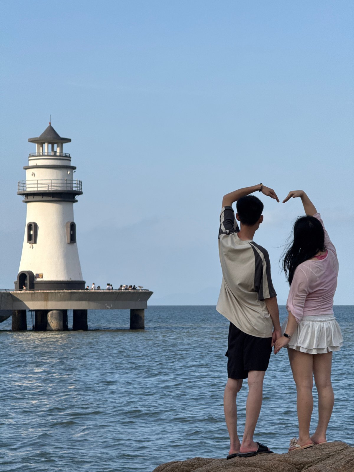 Tourists pose at scenic Xiangzhou coastal lighthouse during morning visit