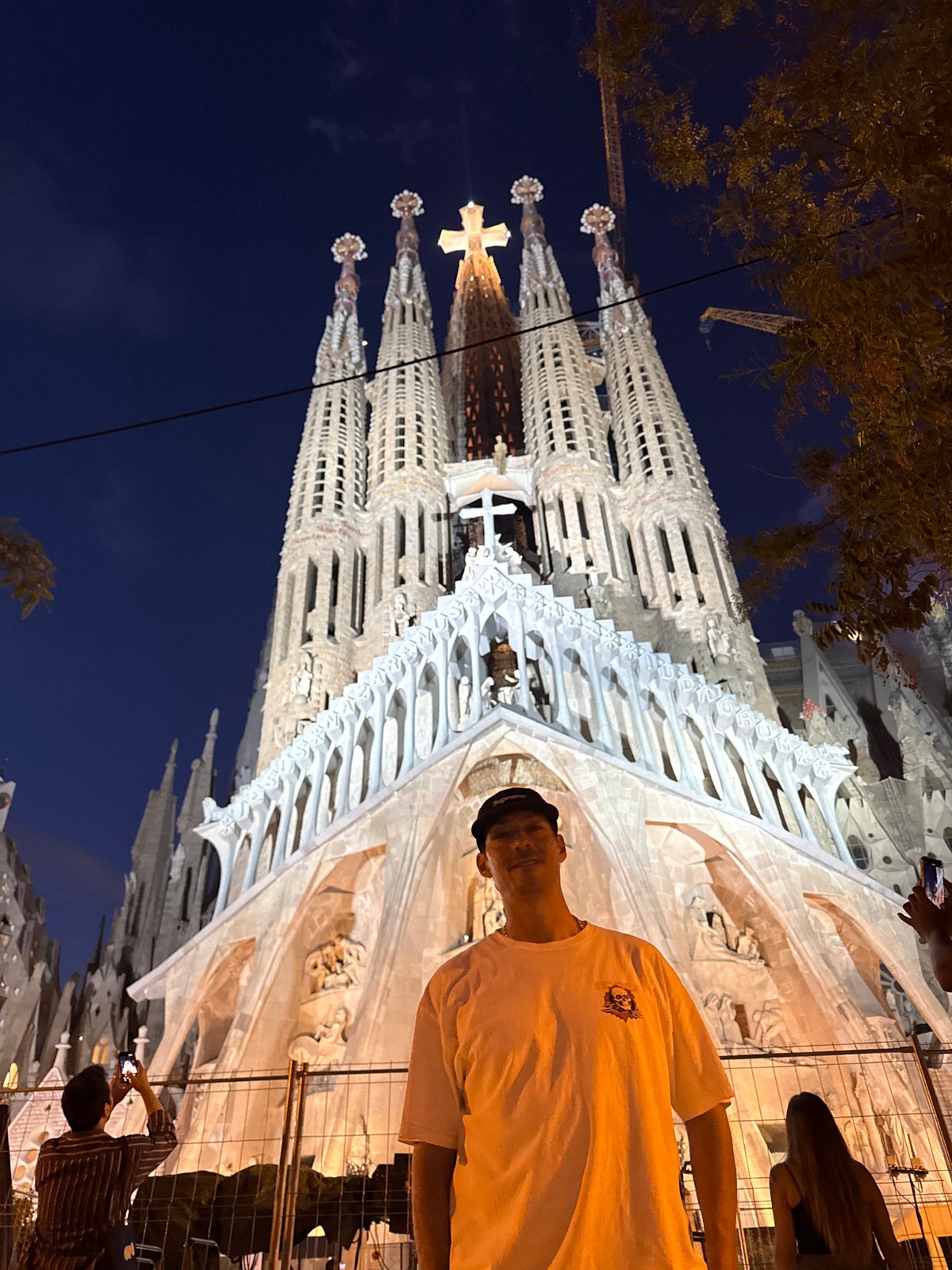 Evening tourists photograph illuminated Sagrada Familia in Barcelona