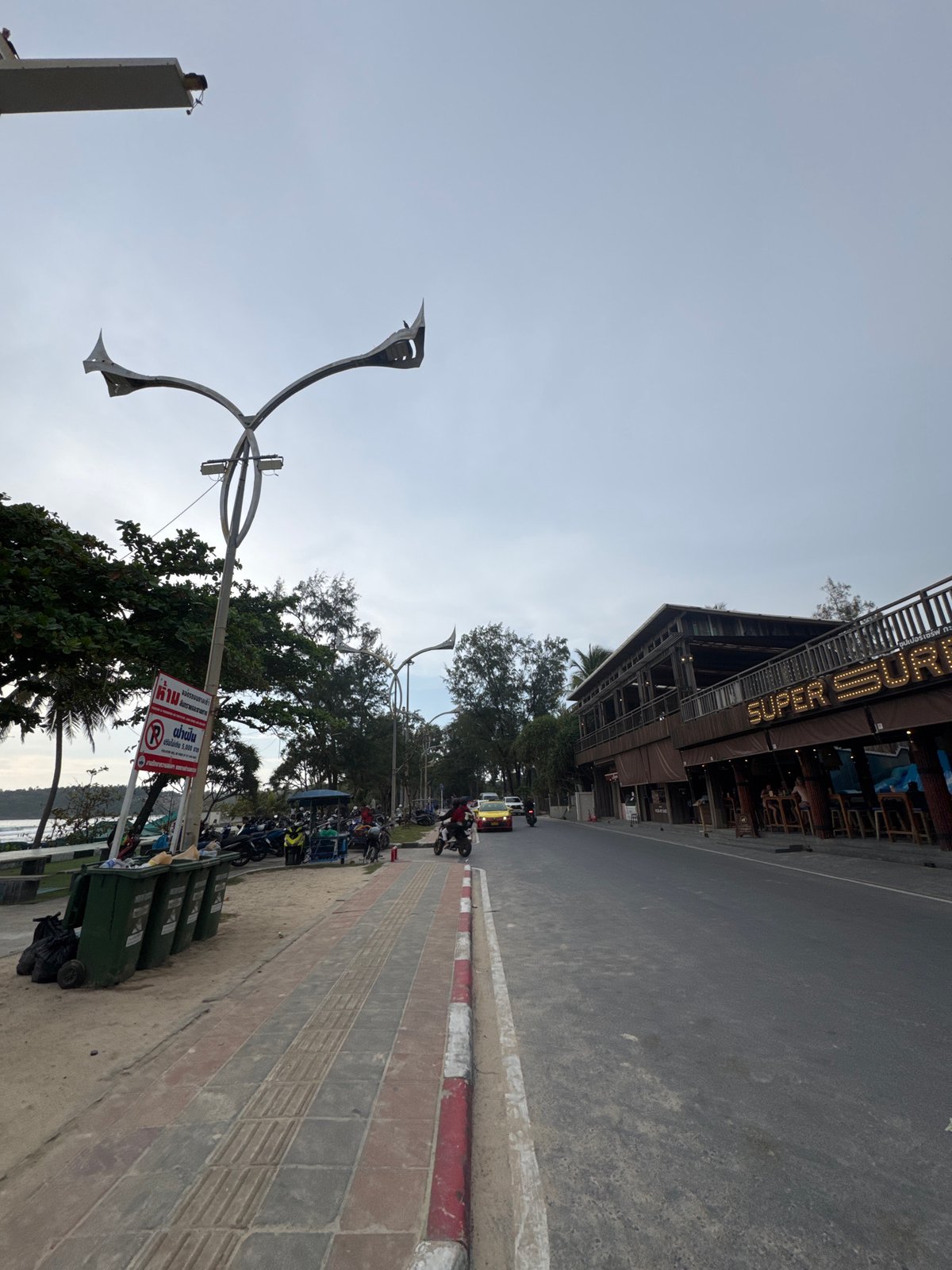Busy morning at Karon Beach — sand, swimmers, and street life
