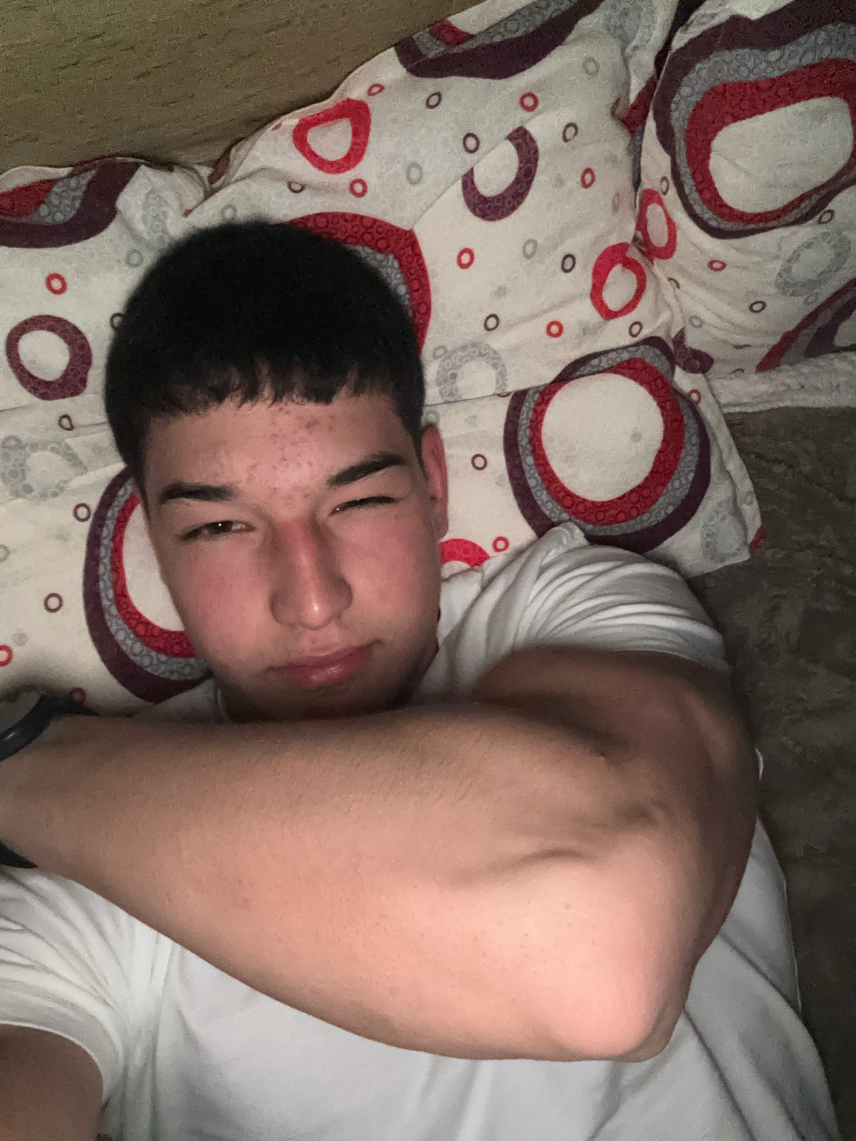 Young man makes playful gestures while lying in bed