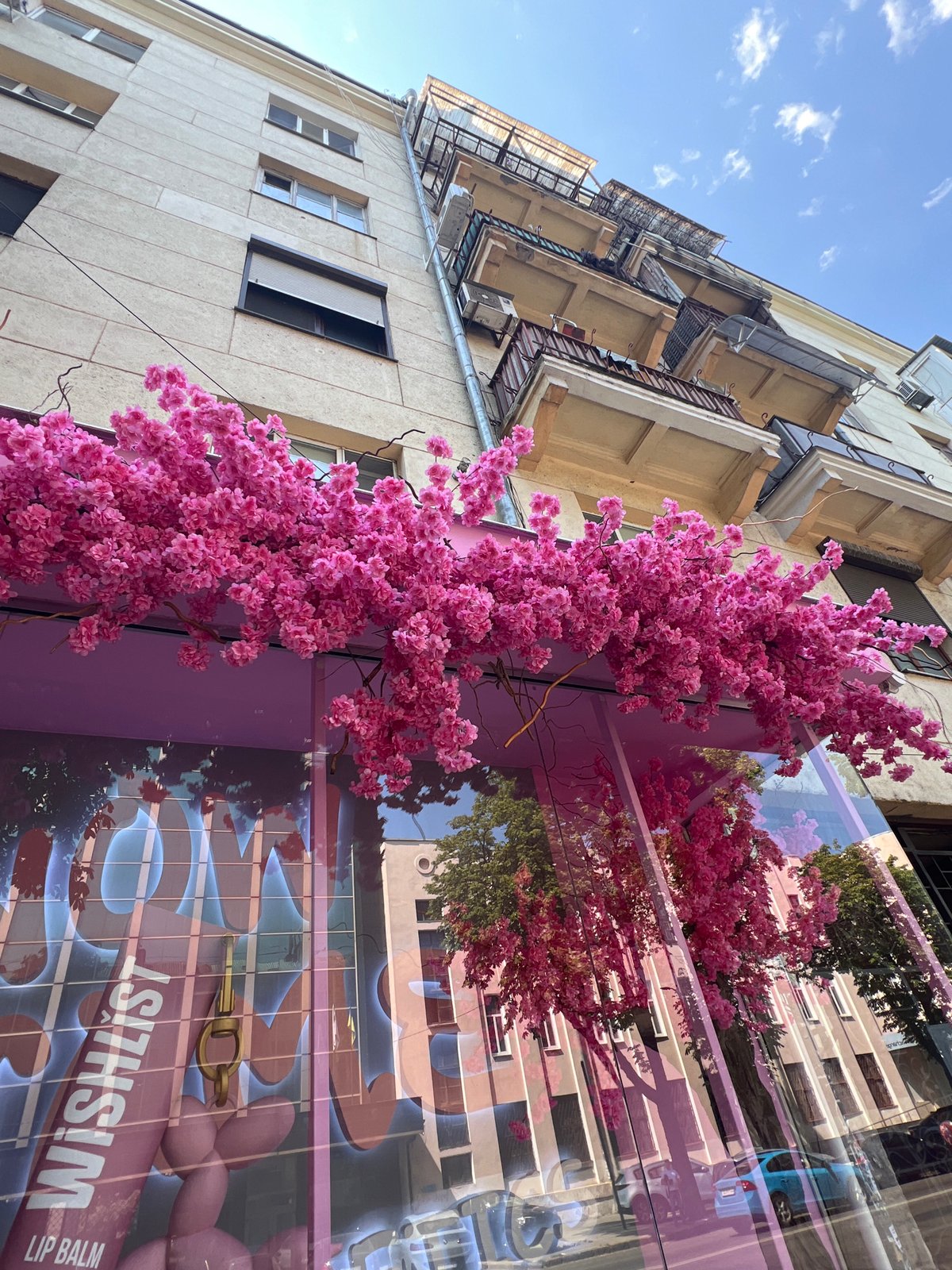 Pink cosmetics storefront with cherry blossoms, Odesa summer street