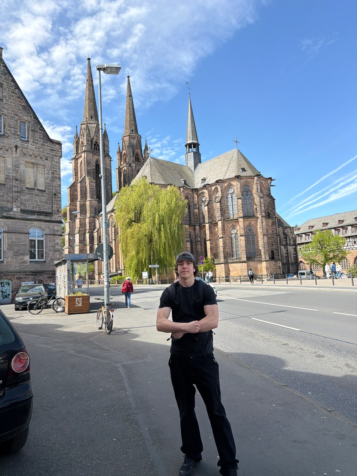 Man photographed on sunny street near gothic church in Marburg