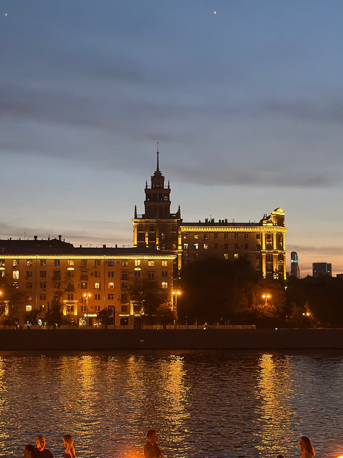 Moscow River at dusk: city lights, riverside deck, people dancing