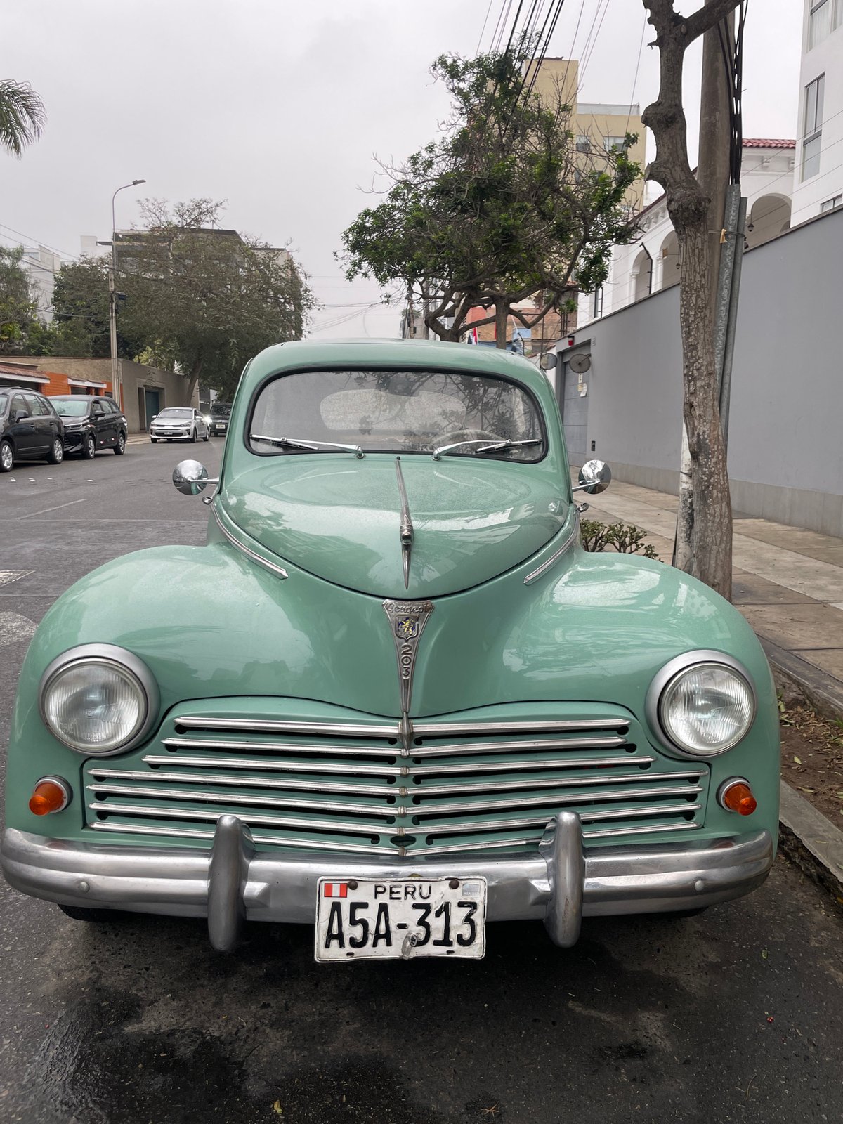 Vintage Peugeot parked on rainy Miraflores street