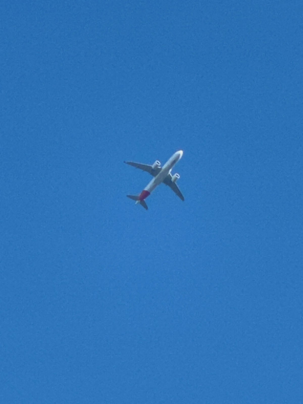 Red-tailed passenger jet crosses clear skies over southeast London