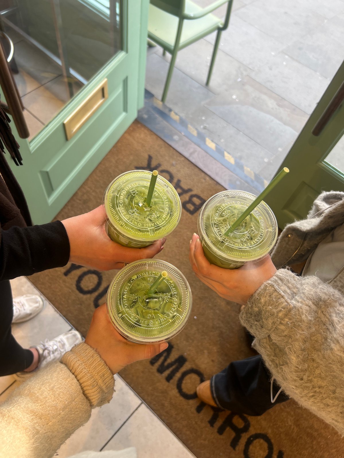 Three people share green drinks in London gathering