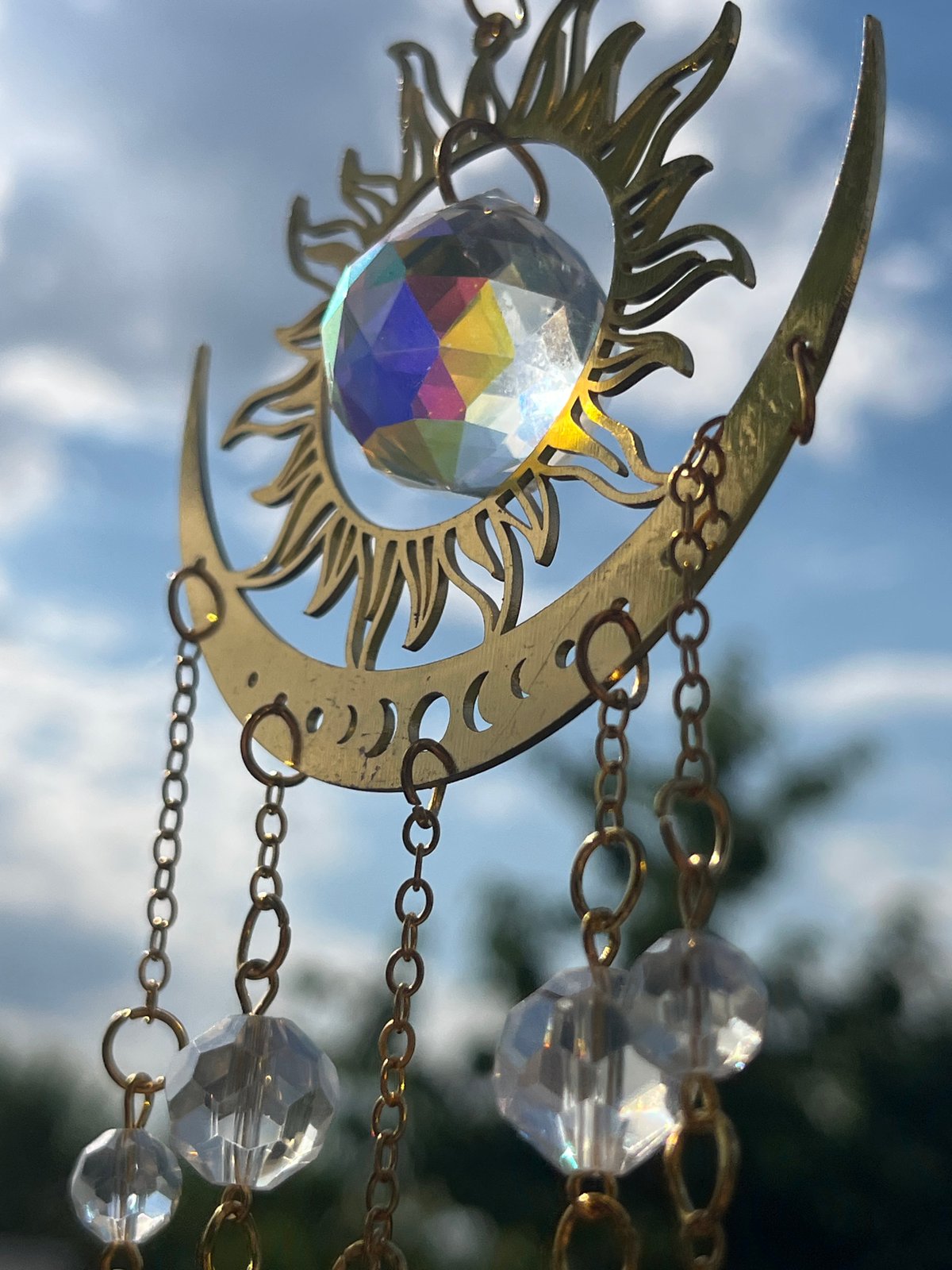 Gold sun and moon suncatcher photographed against a blue sky