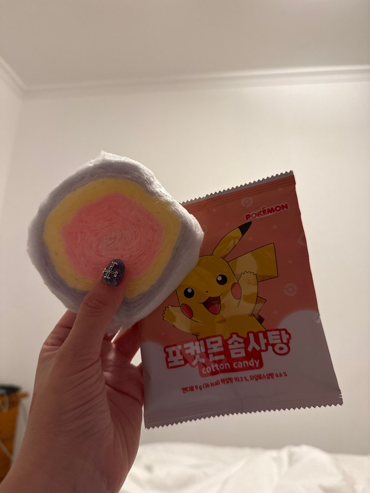 Person holds colorful Pokémon cotton candy at location