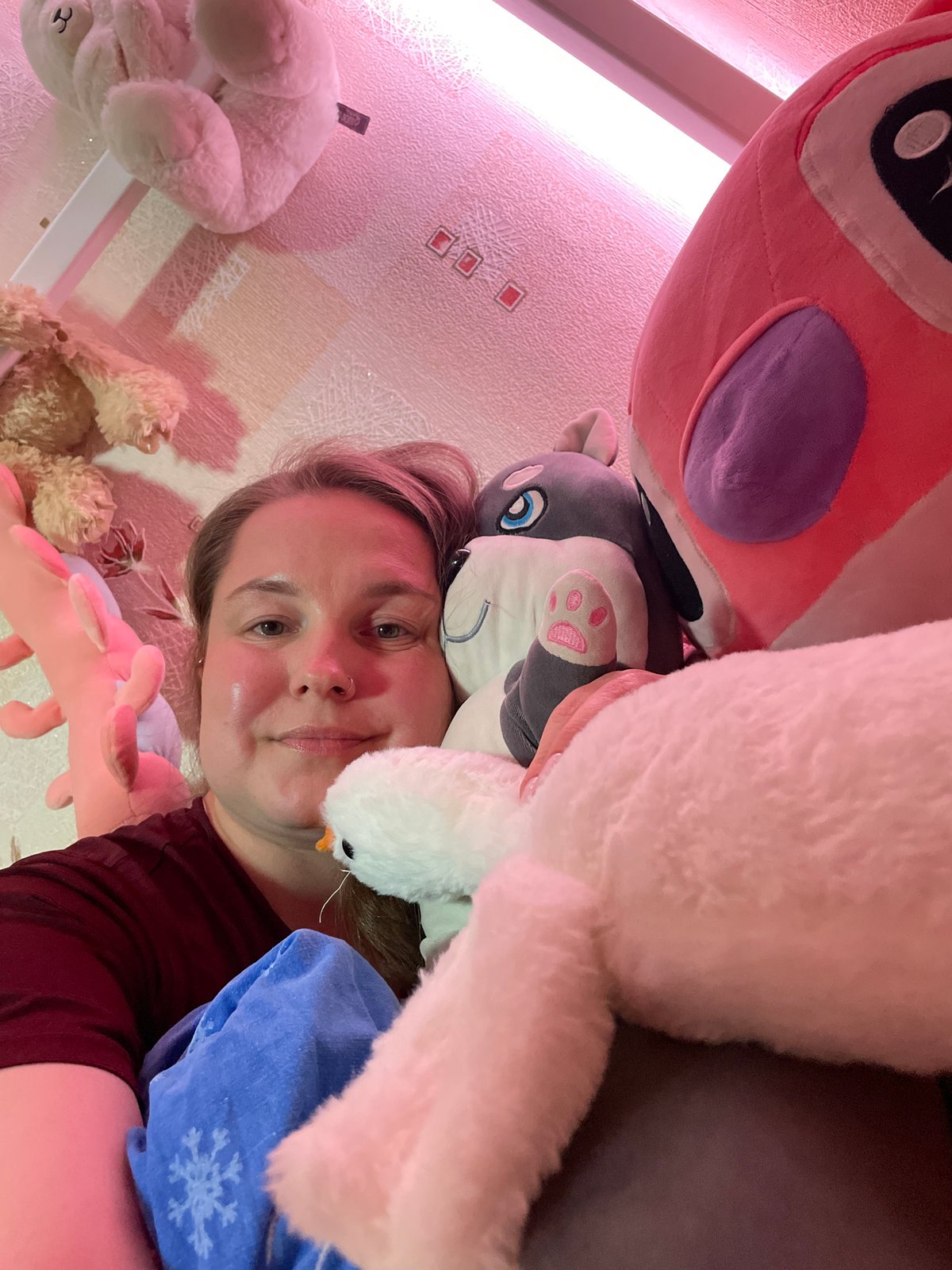 Woman poses with stuffed animal collection in Izhevsk bedroom