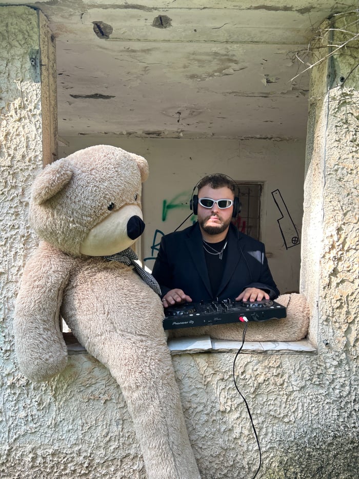 Man poses with teddy bear in abandoned building window