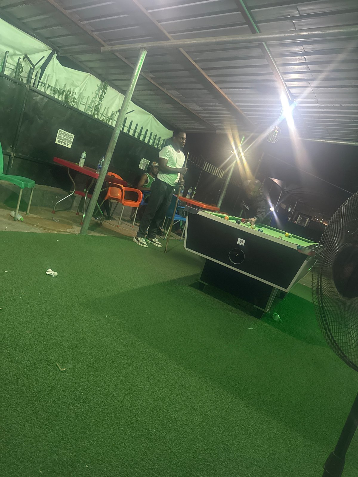 Evening social gathering at outdoor pool hall in Karu