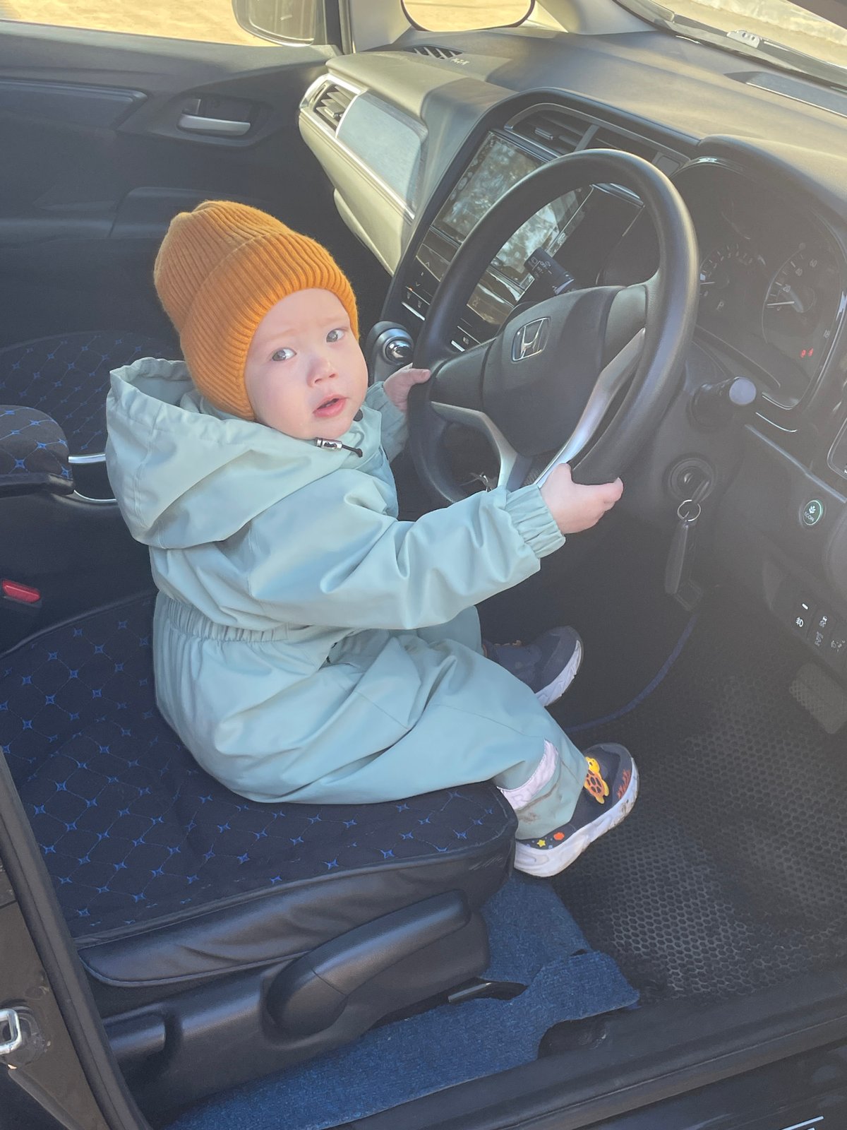 Child plays driver in car seat, Siva Russia