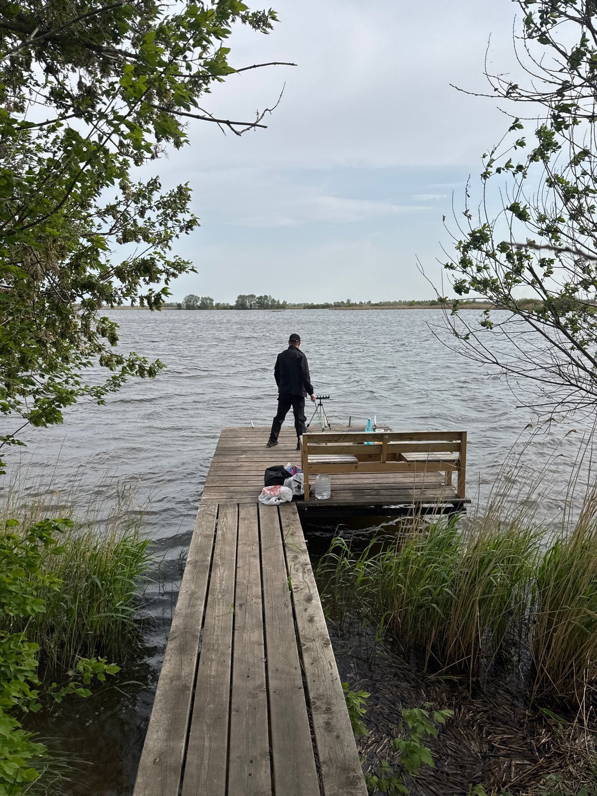 Angler fishes from dock while grill burns nearby