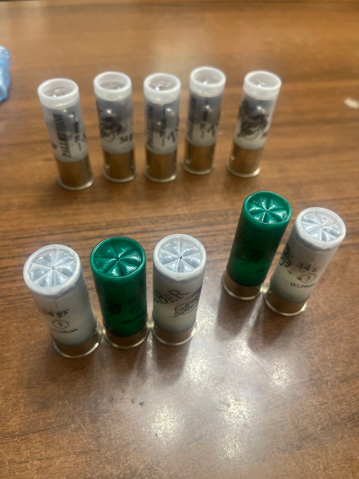 Ten shotgun shells arranged on wooden surface indoors