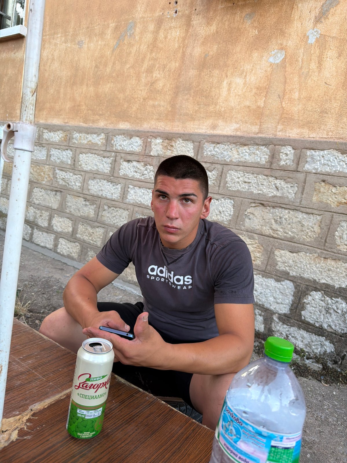 Outdoor table, open beer, phone in hand — Vratsa evening