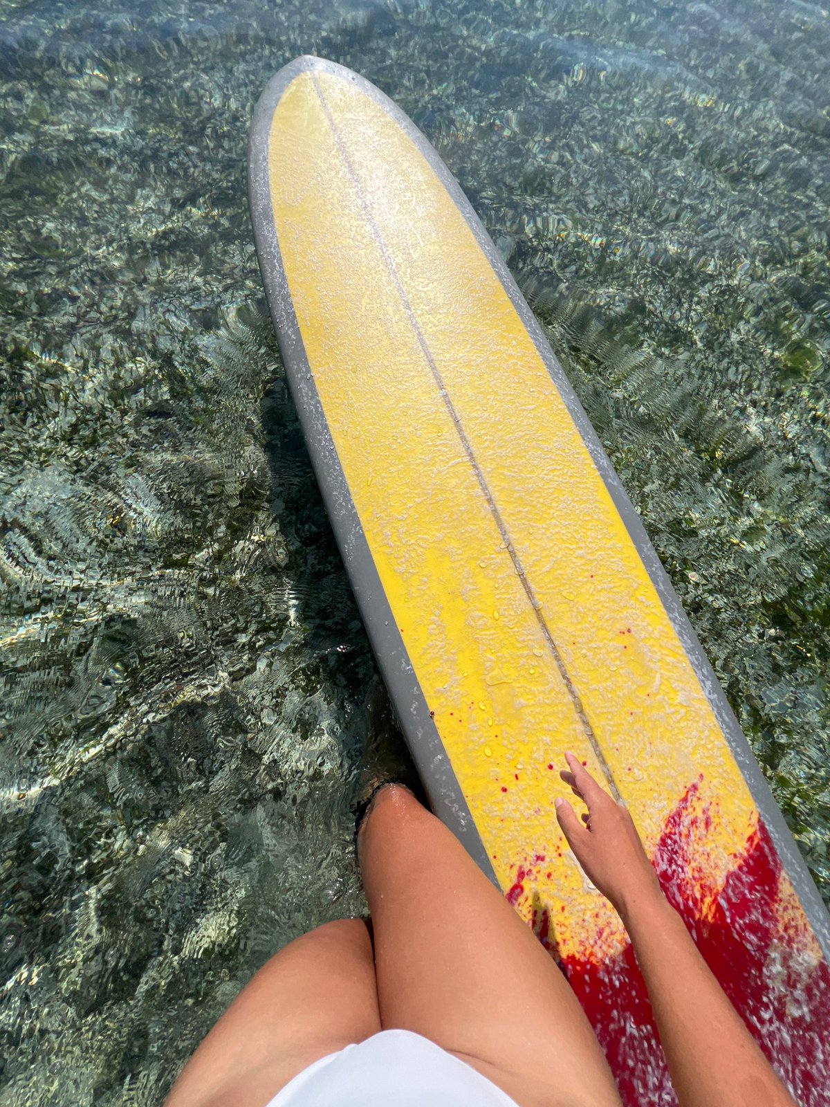 Yellow surfboard drifting through shallow coastal waters near General Luna