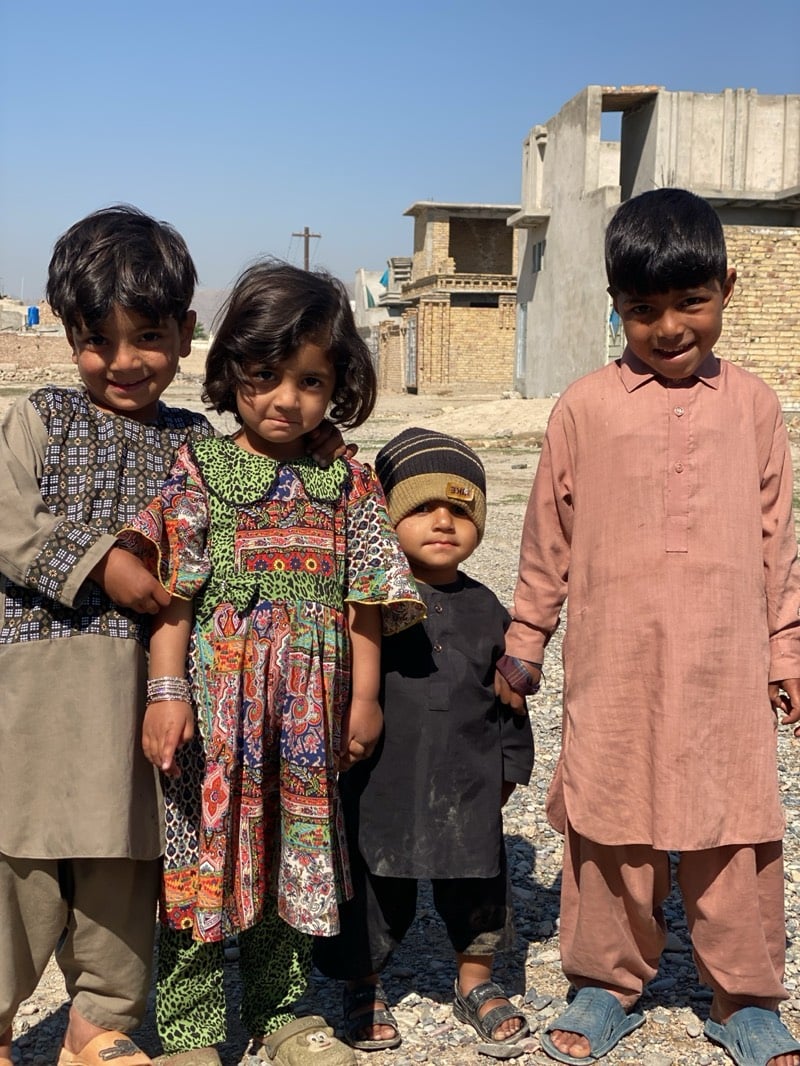 Four children pose for outdoor photograph under clear skies