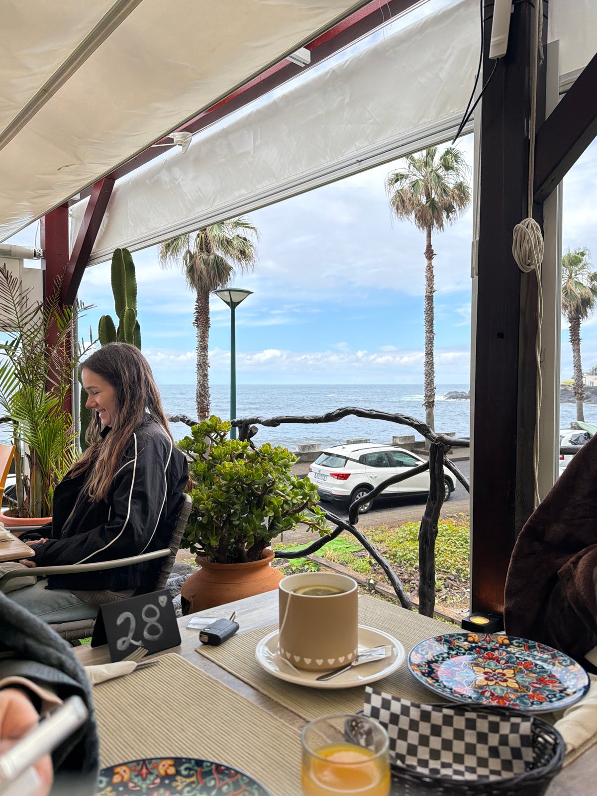Woman enjoys breakfast at coastal cafe in Porto Moniz