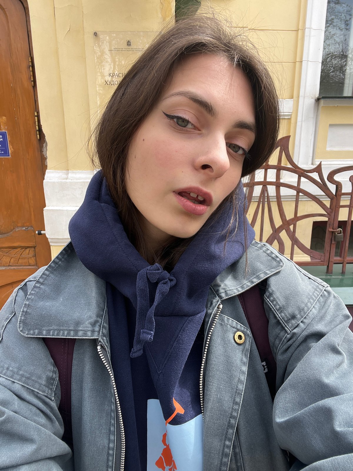 Woman takes selfie in front of yellow building in Krasnoyarsk
