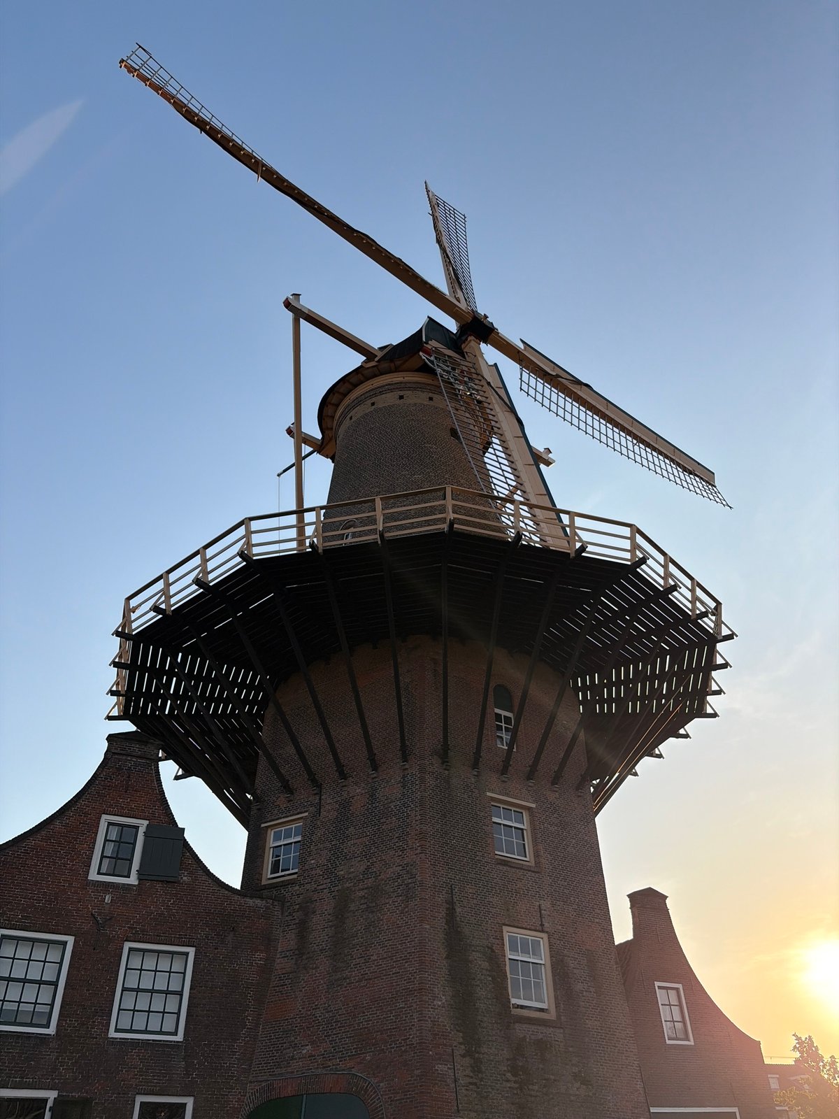 Tourist documents historic Delft windmill and canals during evening visit