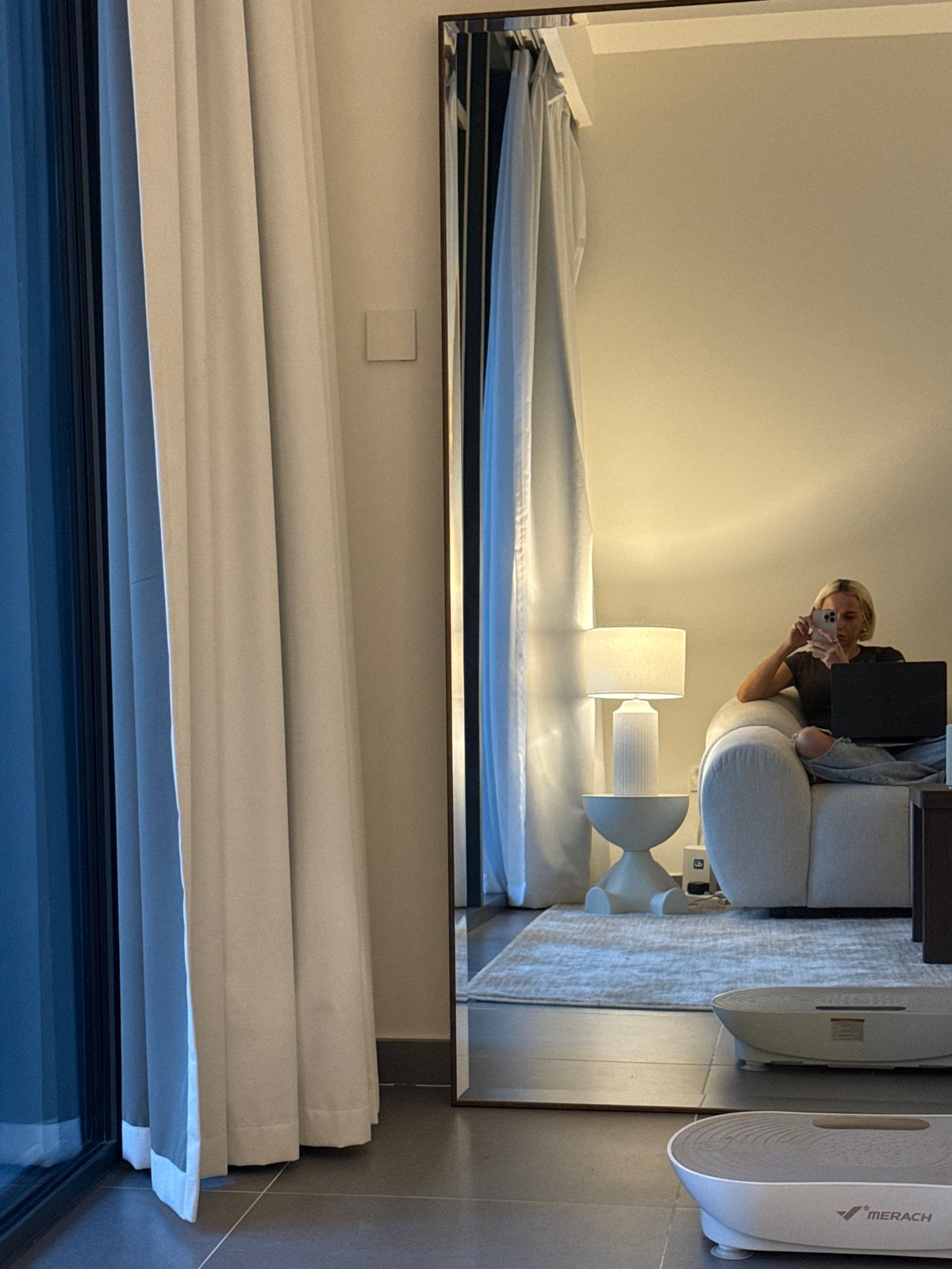 Person multitasks with devices on sofa in Dubai room