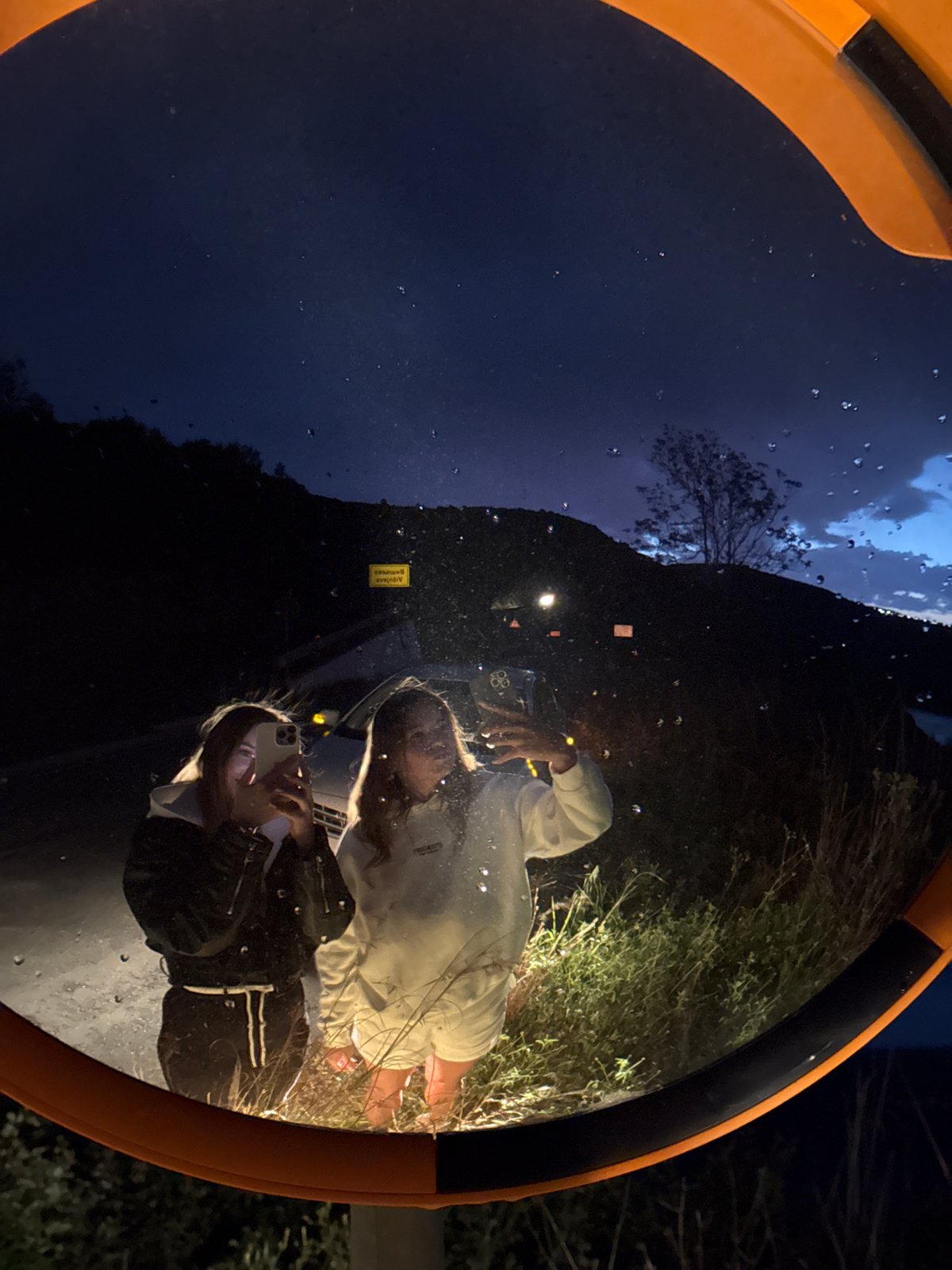 Young women photograph themselves in convex mirror in Montenegro