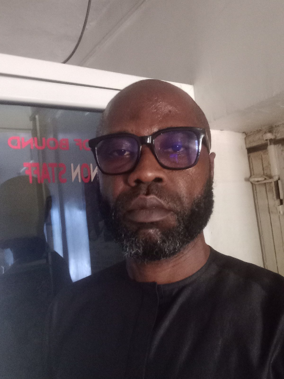 Bearded man in black shirt photographed near window
