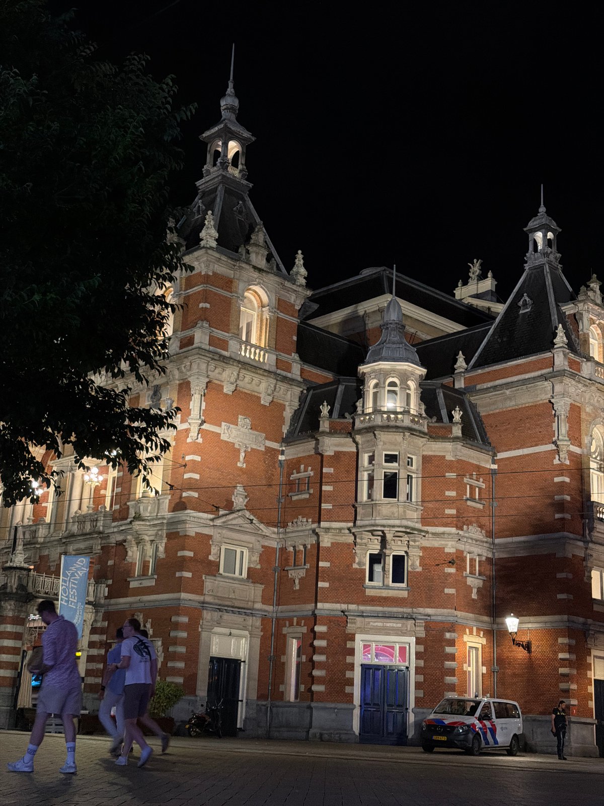Police presence outside ornate Amsterdam building late at night