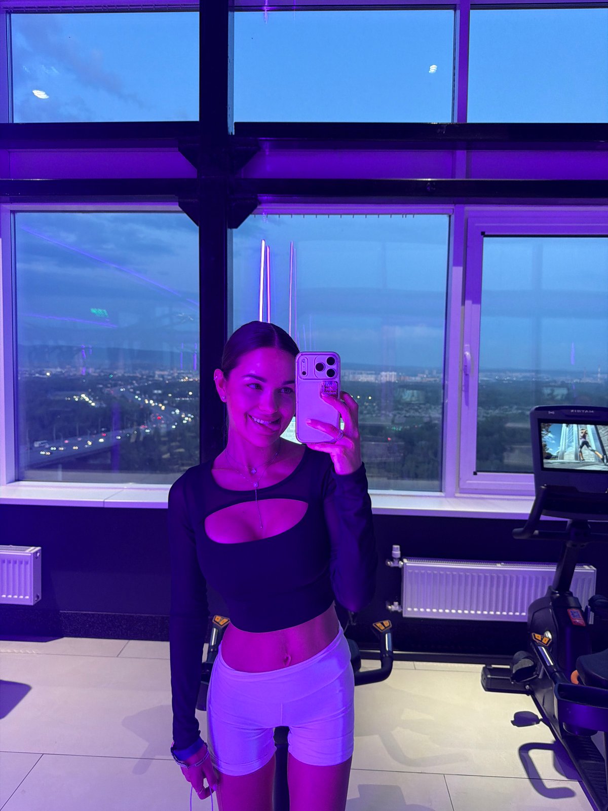Woman takes selfies overlooking Krasnoyarsk cityscape at dusk