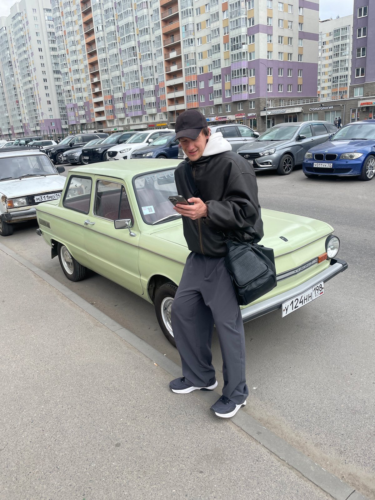 Man poses with vintage Soviet car on Russian street