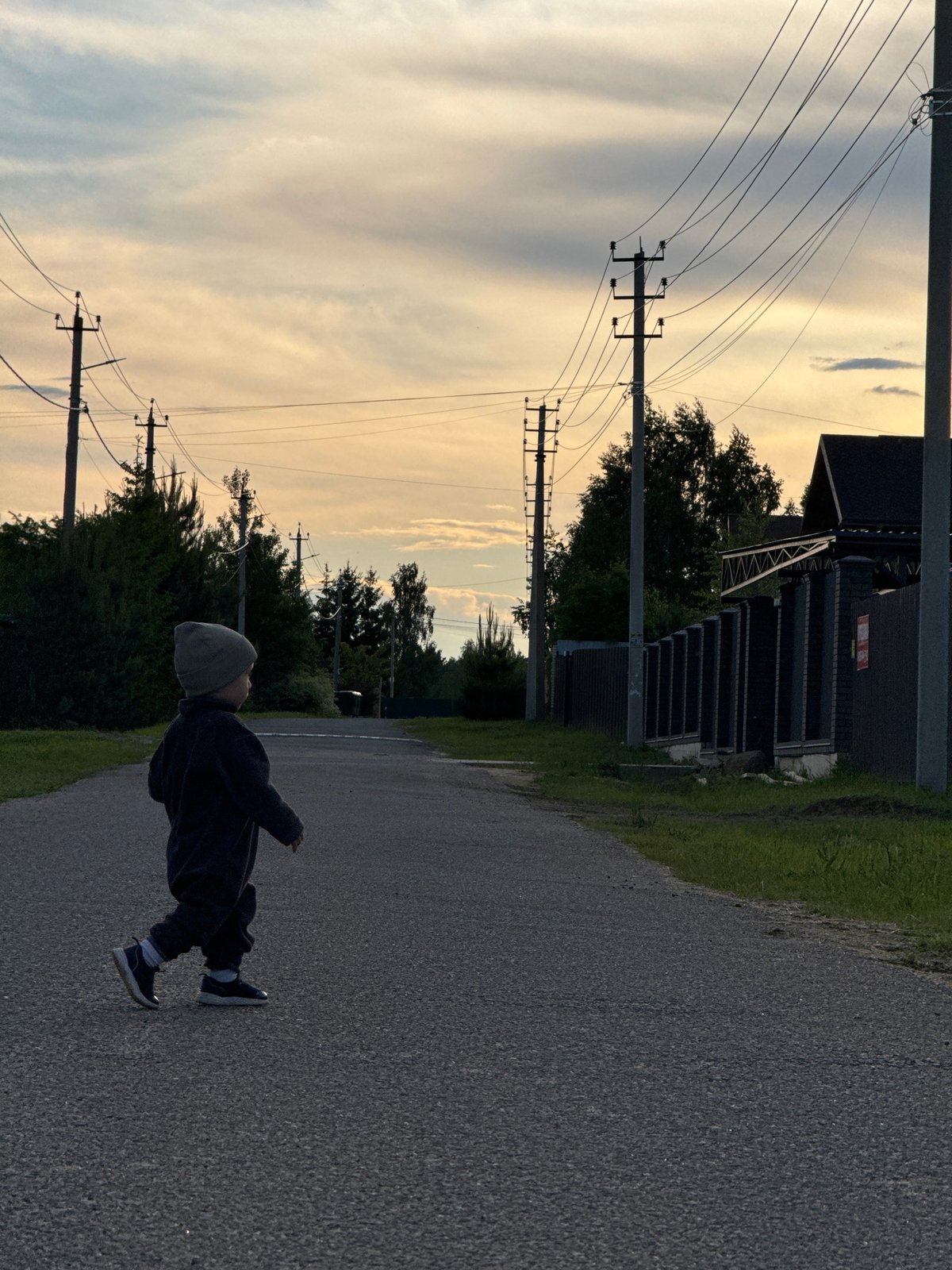 Two pedestrians walk along rural road in Vysokinichi, Russia