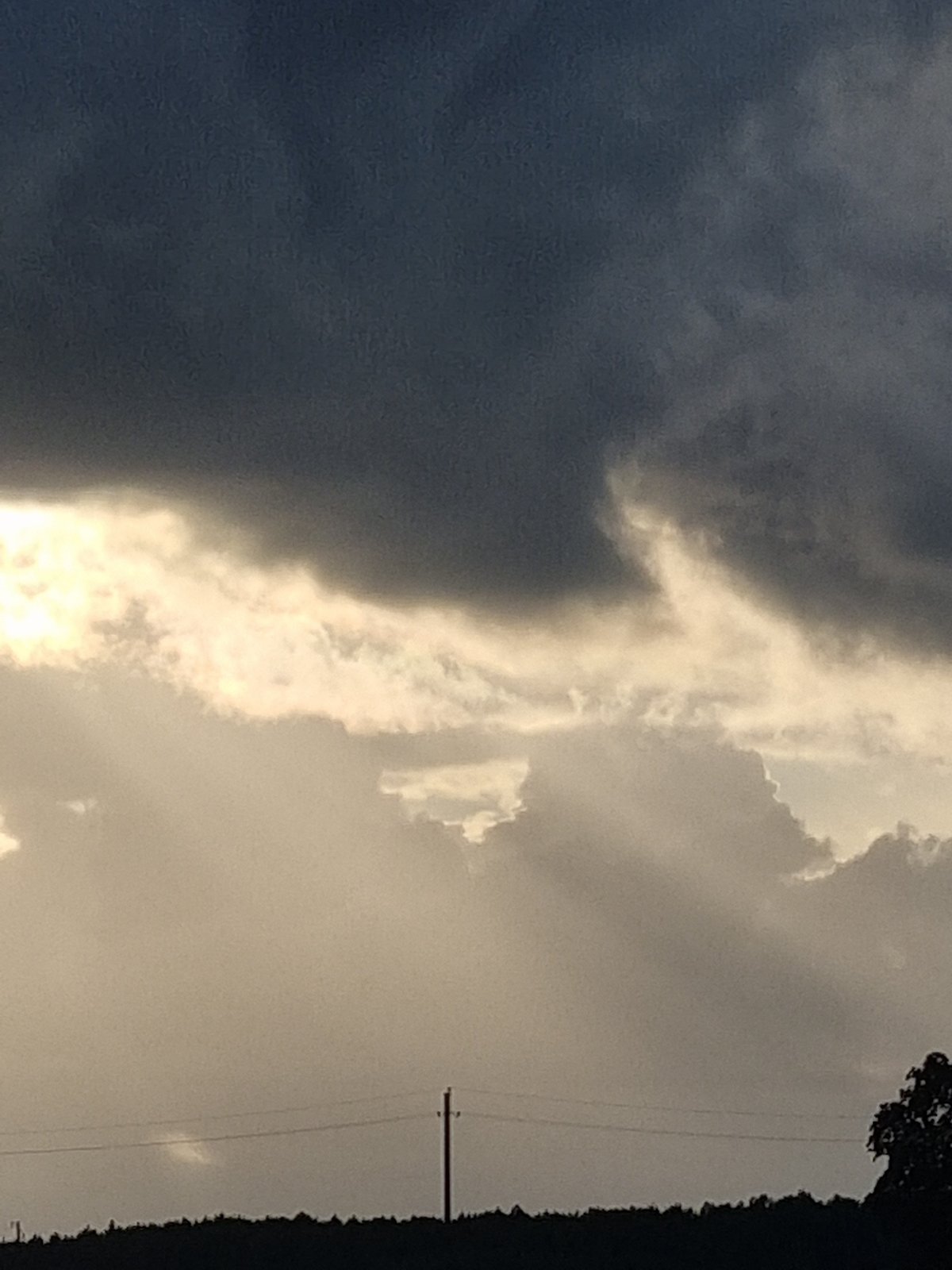 Storm clouds gather over a rural Lithuanian village at dusk