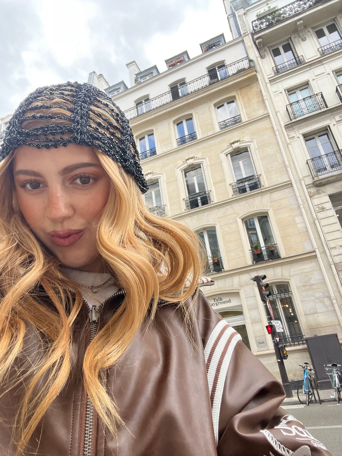 Woman in striped leather jacket photographed outside Paris building