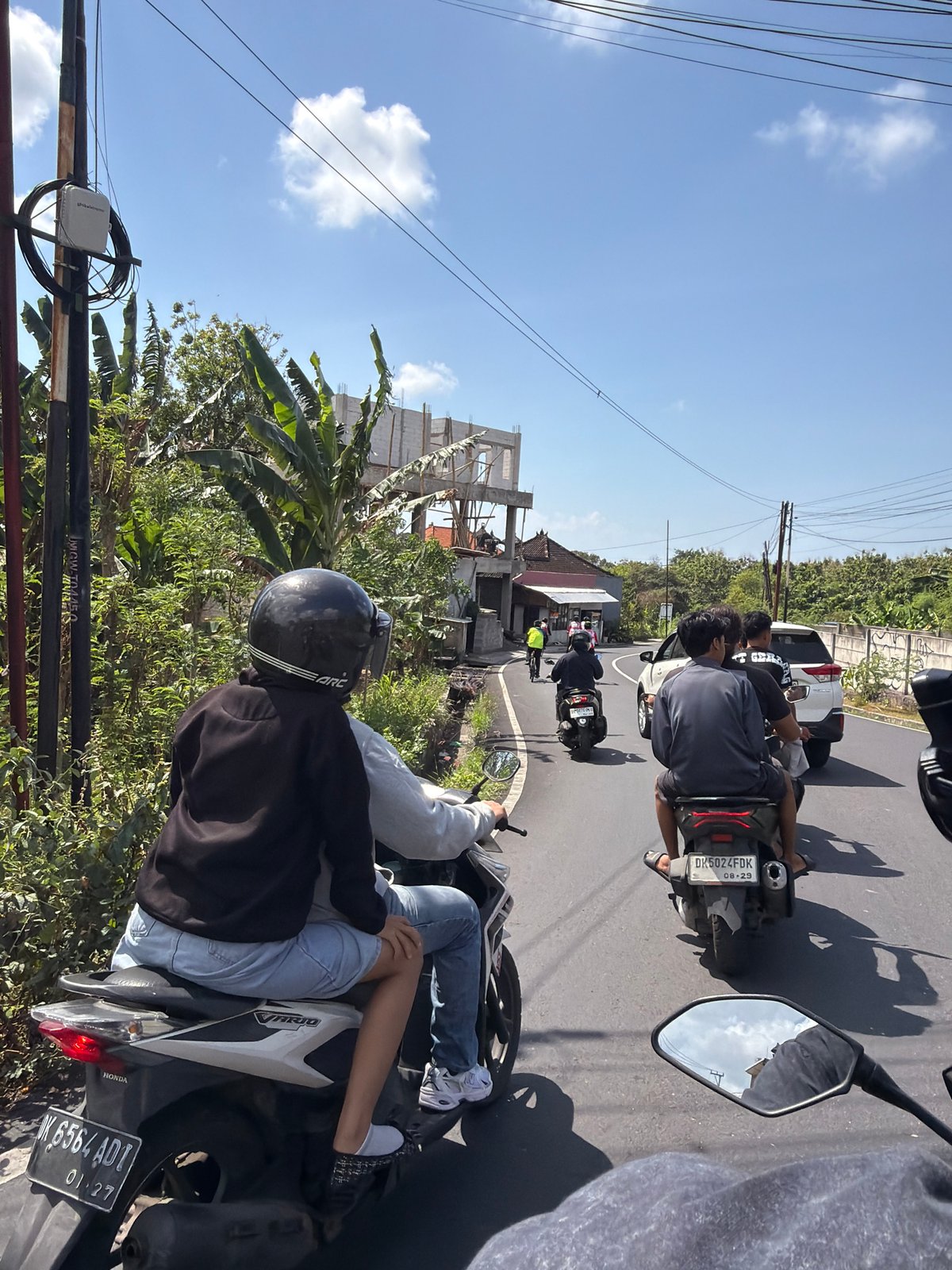 Motorcycles and cyclists navigate sunny Kuta Selatan streets