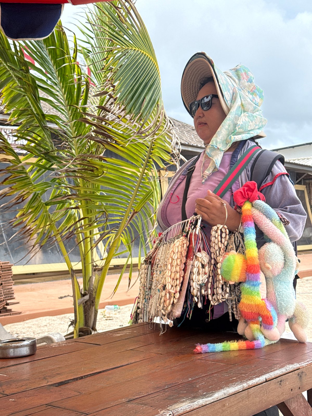 Shell jewelry vendor at a rustic Choeng Thale beach stall