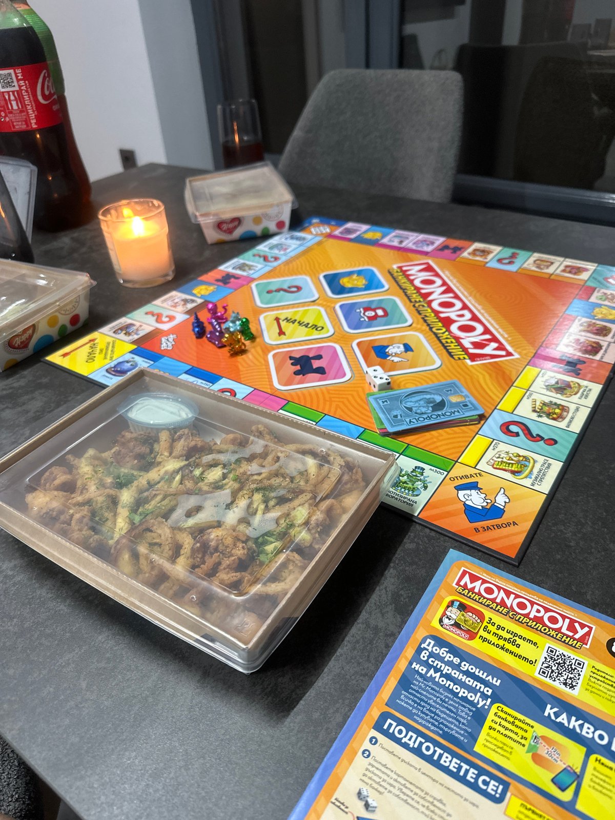 French bulldog plays while owner enjoys Monopoly and takeout