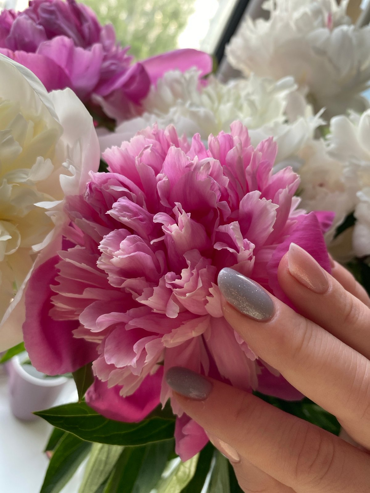 Woman poses with peony bouquet in indoor photo session