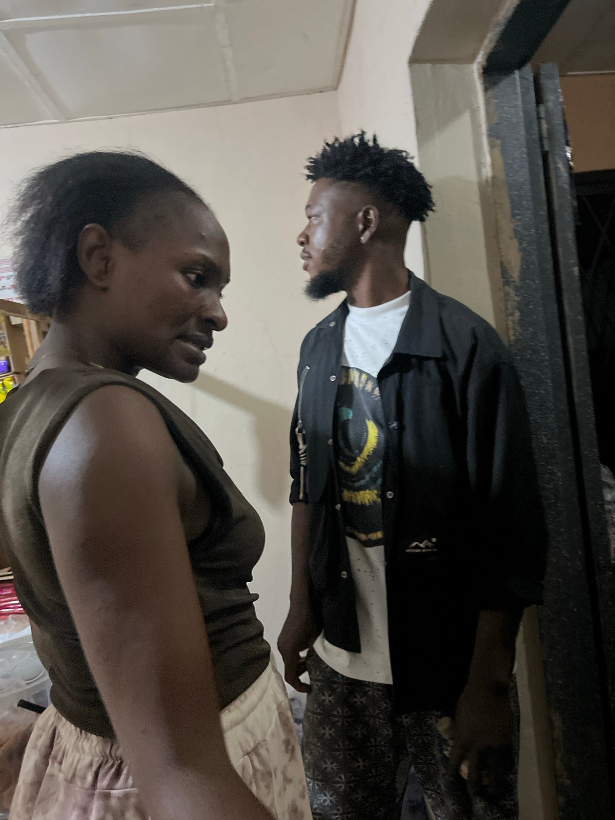 Two people in a dimly lit indoor space, Gura Top, Nigeria