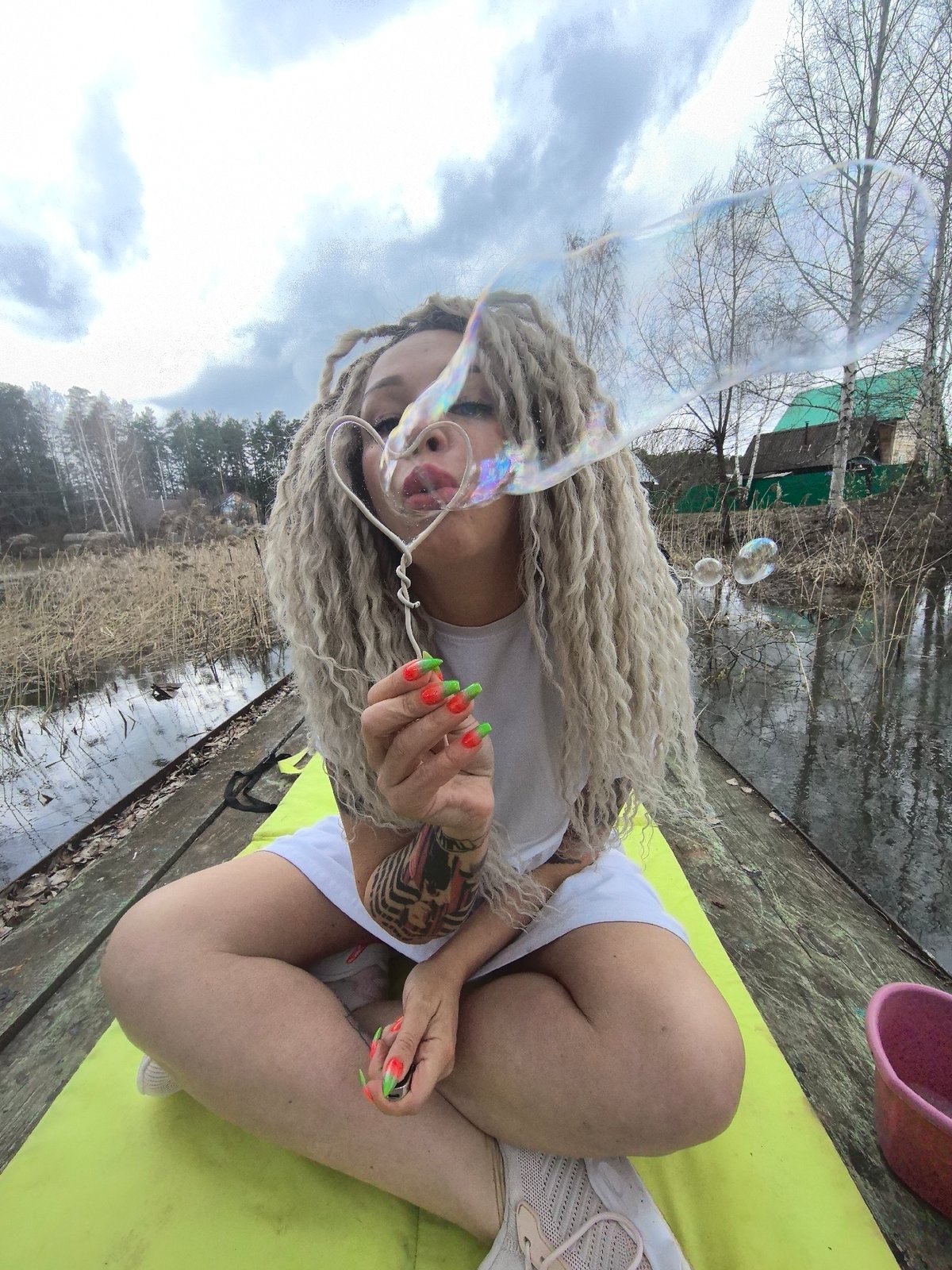 Woman blows bubbles on waterside pier in Noviy, Russia