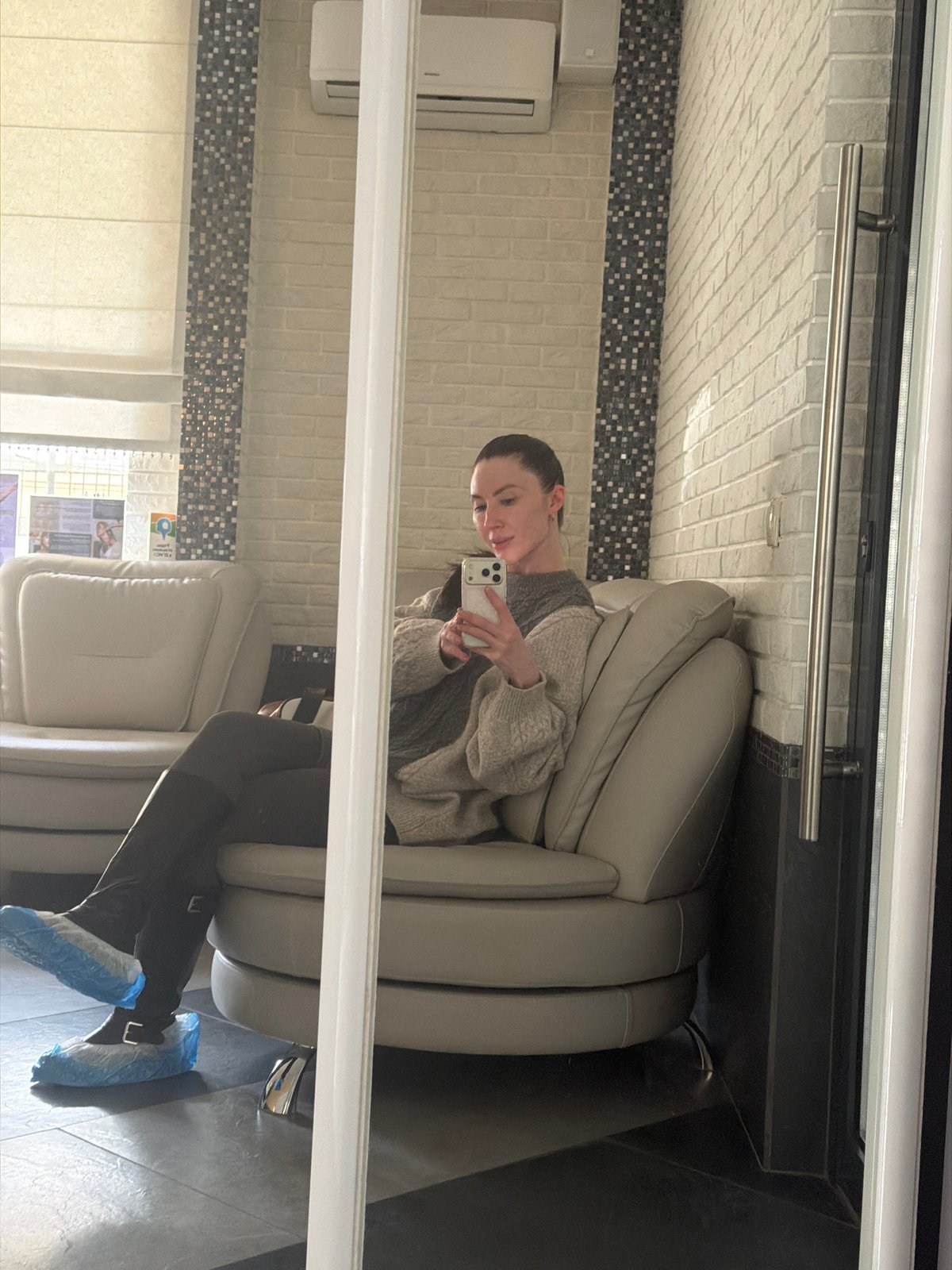Woman takes selfie in chair, captured via mirror reflection