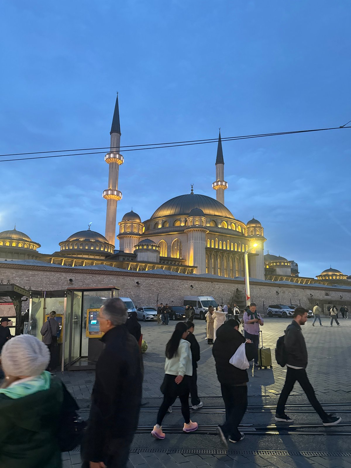 Evening pedestrians gather near illuminated mosques in Istanbul's Beyoğlu